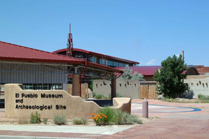 A picture of the building with dark red roof and sign in front. 