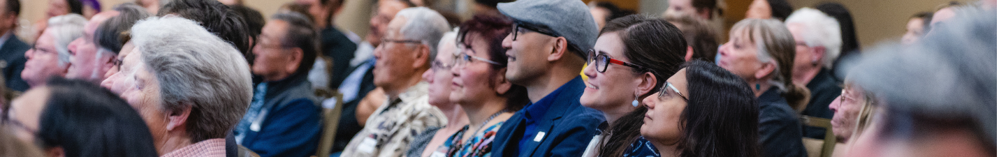 A crowd smiles and listens to a speaker at a History Colorado event.