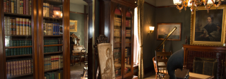 The dark wood library at the Center for Colorado Women's History. There are many books on the shelves and a brass engraved art piece.