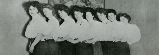 Madam Anna “Gouldie” Gould’s boarders lined up in front of a tapestry