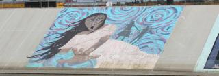 A mural of a woman who appears scared on a colorful background.