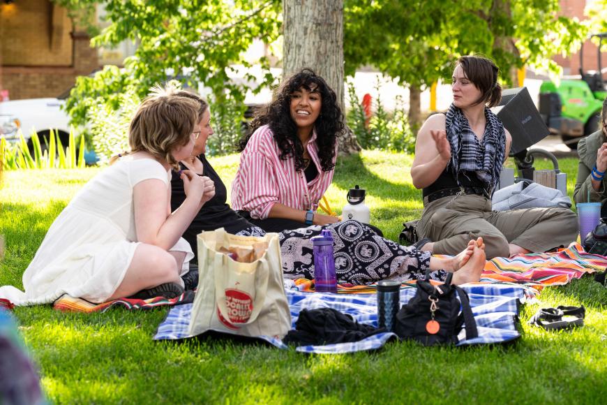 Lawn of the center for Colorado Women's History. Four women sit on a blanket and chat happily.