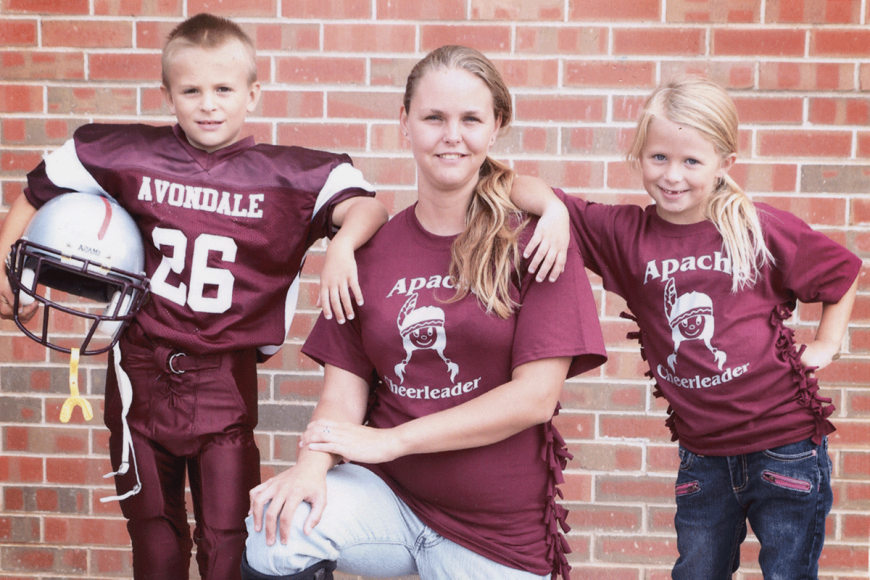 A family of three siblings in Avondale Apache football and cheerleader uniforms smile at camera.