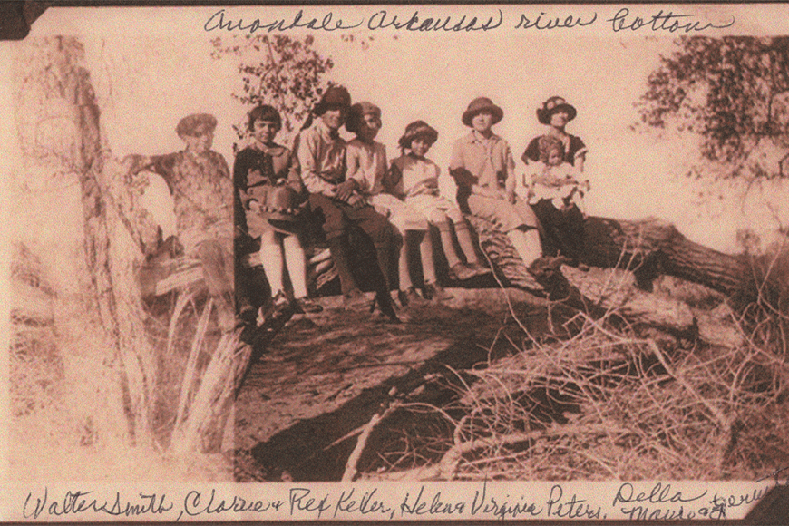 A family of seven children and a bay pose on a large toppled tree overhanding a river bottom.