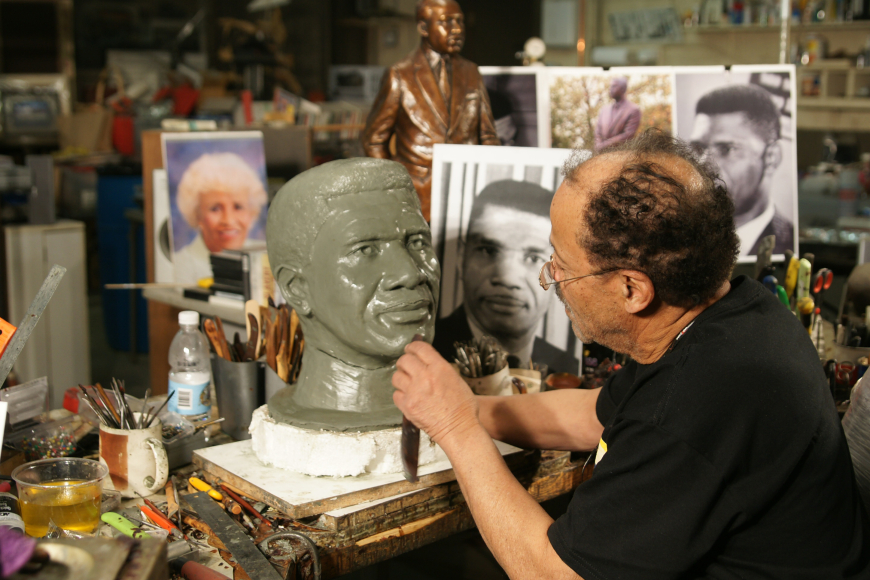 Ed Dwight sculpting a bust of a male figure.