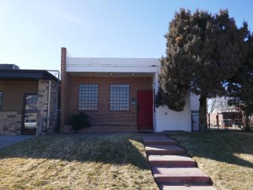 Photo is of a small mid-century modern building with a brick facade and glass block windows. 