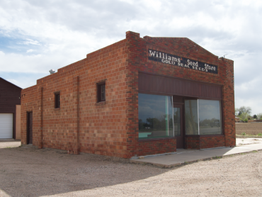 Photo is of a one store brick building with central storefront entrance.