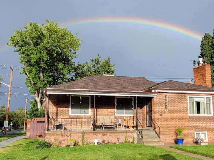 A house with a full arc rainbow overhead.